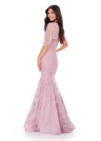 Make a statement in the Ashley Lauren 11431 Long Prom Mermaid Dress. This elegant gown features intricate beading and an asymmetrical cape, creating a stunning silhouette that will turn heads. Perfect for formal occasions and pageants, this dress will make you feel confident and glamorous. Classy with a twist. This fully beaded gown features a sheer asymmetric cape and feathers throughout the skirt.