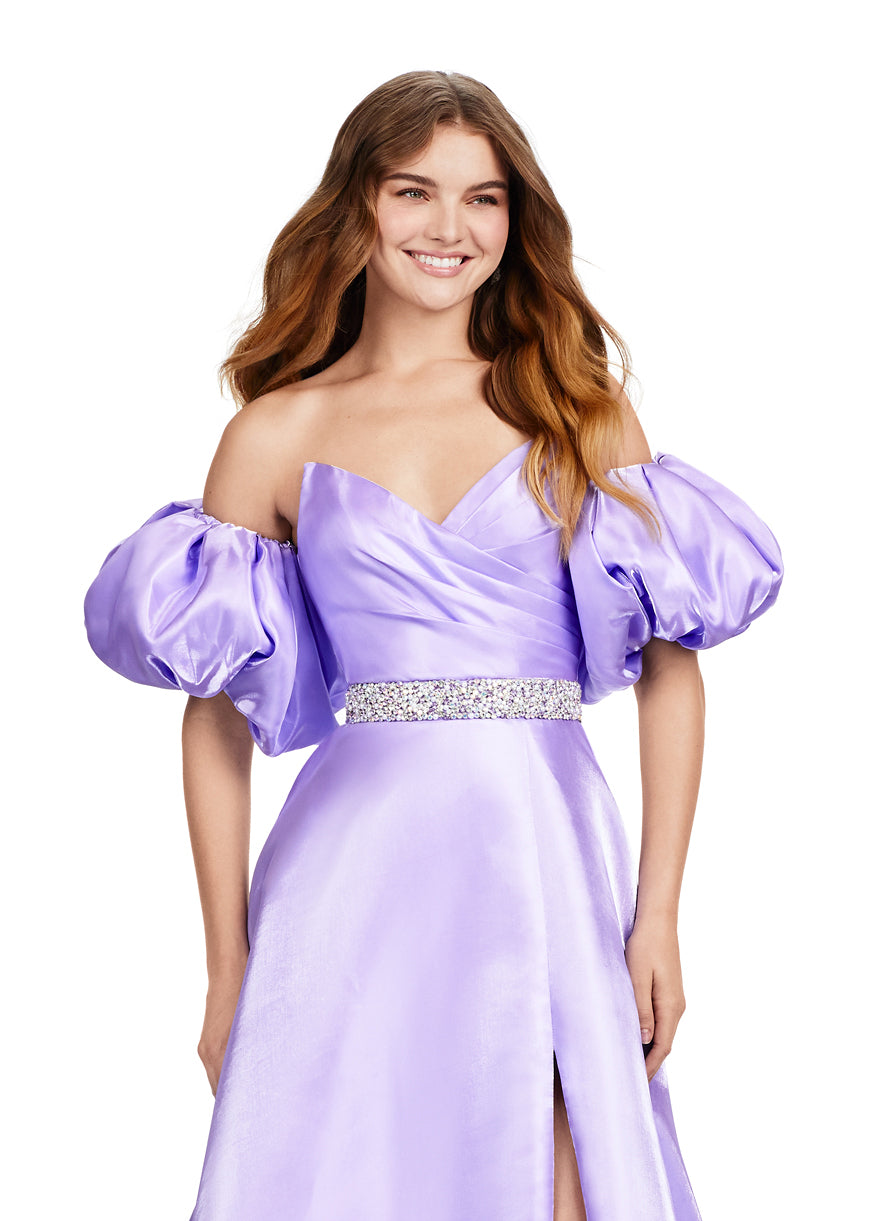 Elevate your formal look with the Ashley Lauren 11474 Long Prom Dress. This elegant strapless satin ball gown boasts a beaded belt, detachable puff sleeves, and a timeless pageant-style design. Perfect for making a statement at any event, this dress exudes sophistication and style. Be memorable in this strapless satin ball gown. This dress features a beaded belt detail, a left leg slit and detachable puff sleeves.