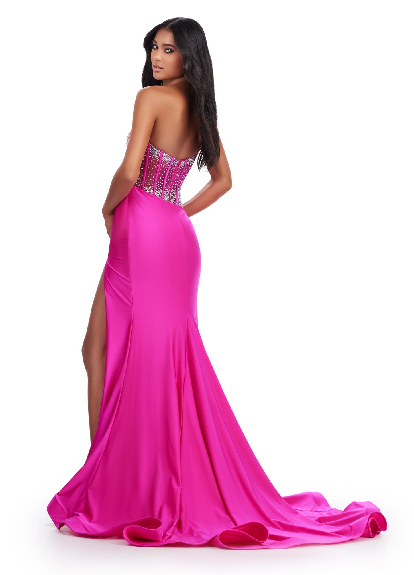 The Ashley Lauren 11617 Evening Gown is crafted from sheer fabric with a one shoulder design adorned with delicate crystal embroidery. The fitted silhouette features a corset bodice with a maxi slit and long train with a voluminous skirt. Perfect for prom, pageants, and formal events. Elegance with a twist! This one shoulder jersey gown features a stunning beaded corset bustier for an added touch of glam.  COLORS: Purple, Magenta, Peacock, Black Sizes: 00-24