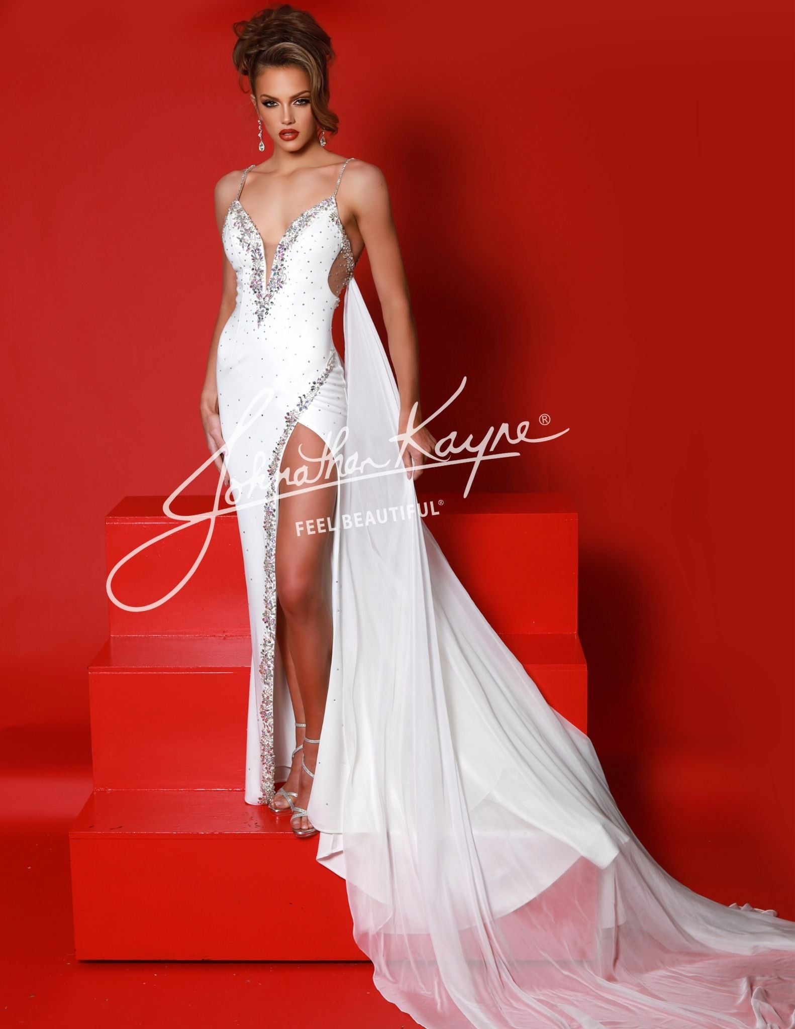 Become the center of attention in this Johnathan Kayne 2954 Long Crystal Slit Cape Pageant Dress. Featuring a V-neck and plunging neckline, this formal gown is embellished with shimmering crystals and features a dramatic slit cape.