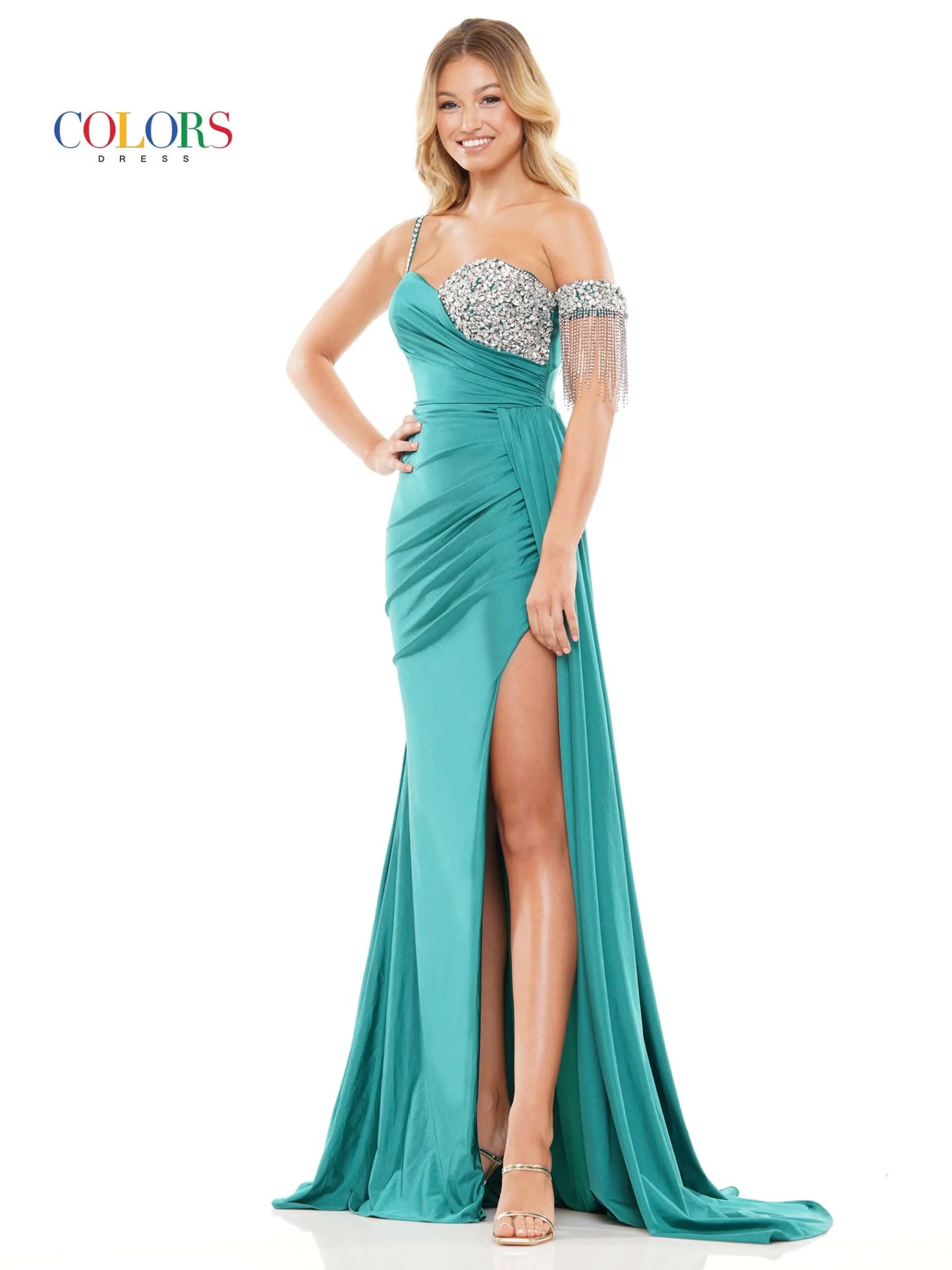 Step onto the red carpet in style with the Colors Dress 3275 Fitted Ruched Slit Overskirt Prom Dress. The one side off the shoulder design is embellished with eye-catching crystal details, while the fitted silhouette is accentuated with a ruched overskirt and fringe detailing. Be the standout at any pageant or prom with this beautiful and glamorous dress.  Sizes: 0-22  Colors: Black, Royal, Deep Green, Hot Pink