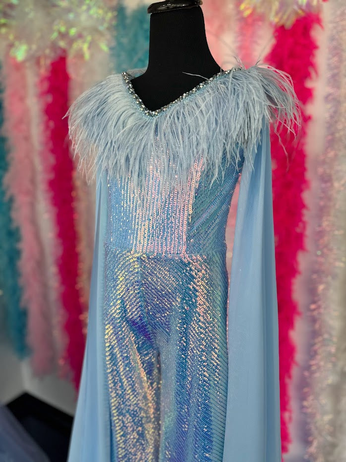 Ava Presley 38046 Long Sequin Jumpsuit is a delightfully fun fashion choice for girls. The detachable capes and feather bodice add playful panache for a statement-making look. The perfect pick for any occasion.  Sizes: 8  Colors: Powder Blue