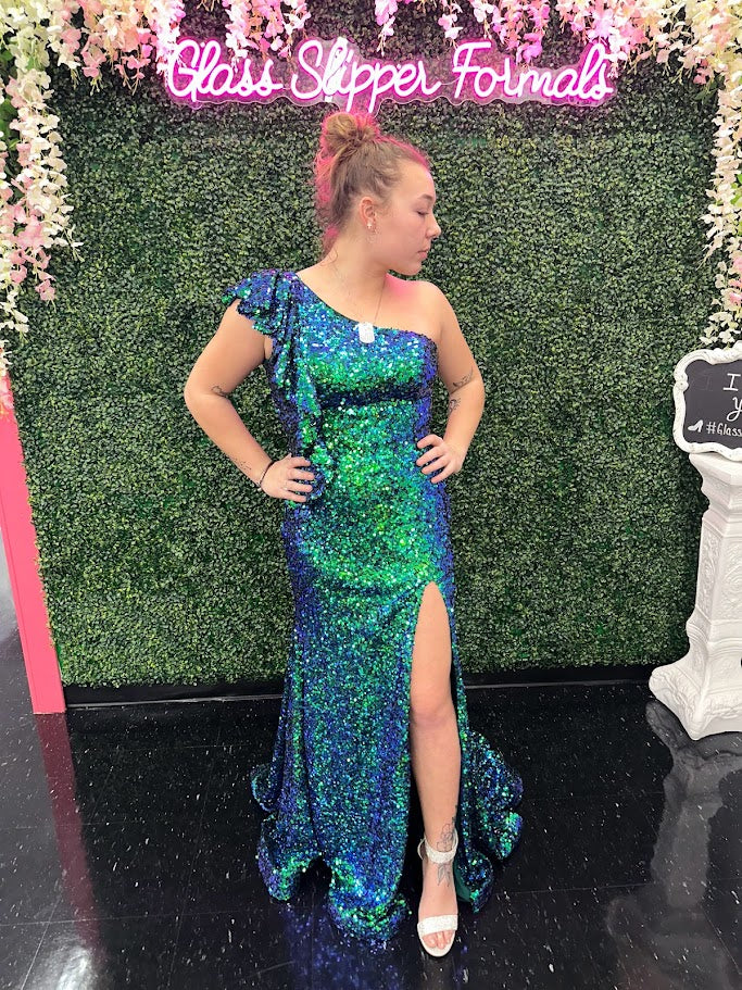 Ava Presley's 39280 Prom Dress is sure to make a stunning statement. Crafted from iridescent sequins, this one-shoulder gown features a ruffle-trimmed neckline, and a dramatic side slit. Perfect for prom, pageants, and other special occasions.  Sizes: 00-24  Colors: Iridescent Hot Pink, Iridescent Teal, Iridescent Light blue