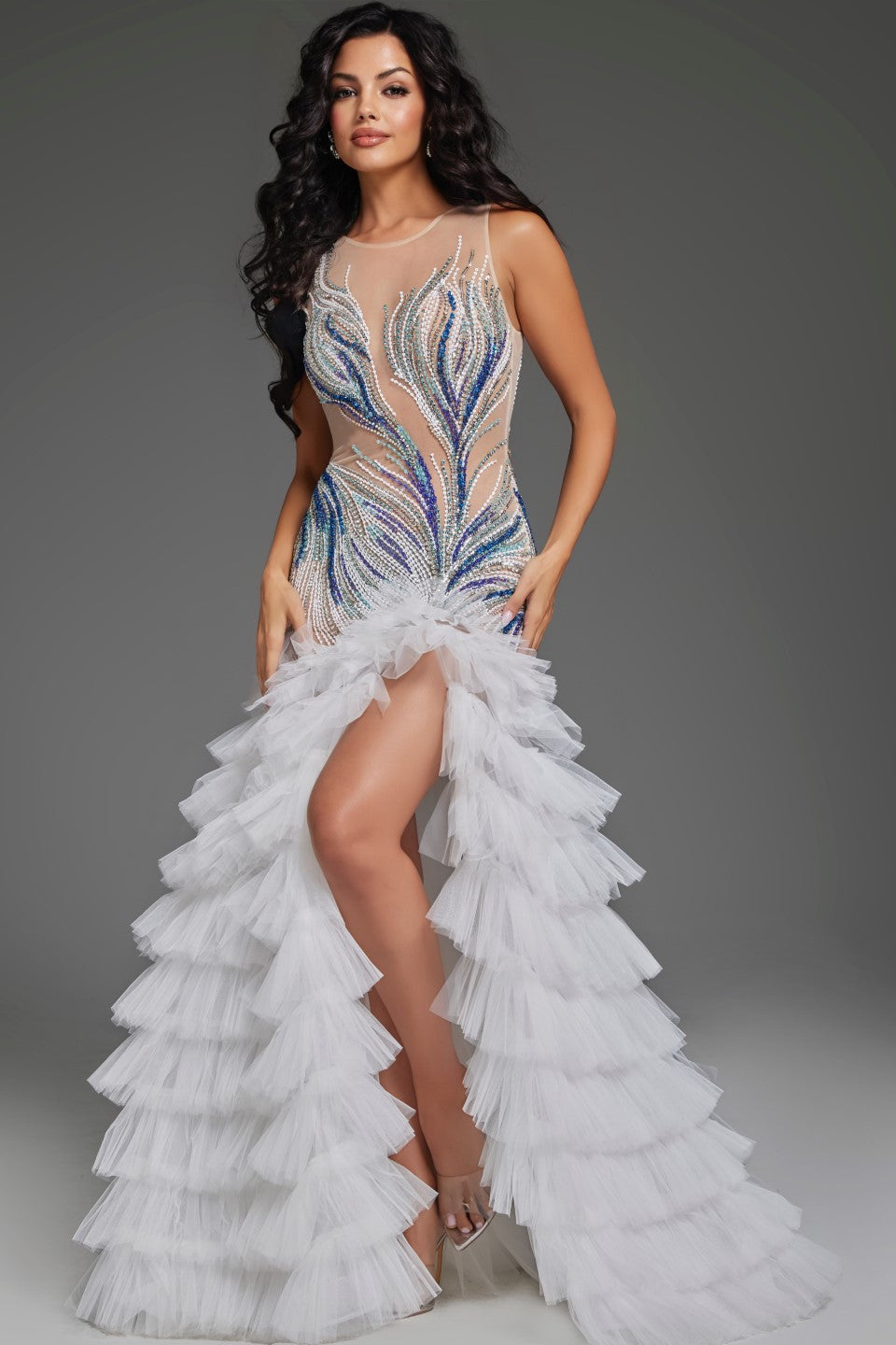 Expertly crafted for pageants, this Jovani 39846 dress boasts a sheer mermaid silhouette, ruffled detailing, and intricate crystal beadwork. With a layered design and a dramatic maxi slit, this formal gown is perfect for making a statement on stage. Shine bright and exude confidence in this show-stopping dress. Make a statement in this captivating gown featuring an illusion neckline that beautifully highlights the intricate beadwork on the bodice. The fitted silhouette through the hips elegantly transitions