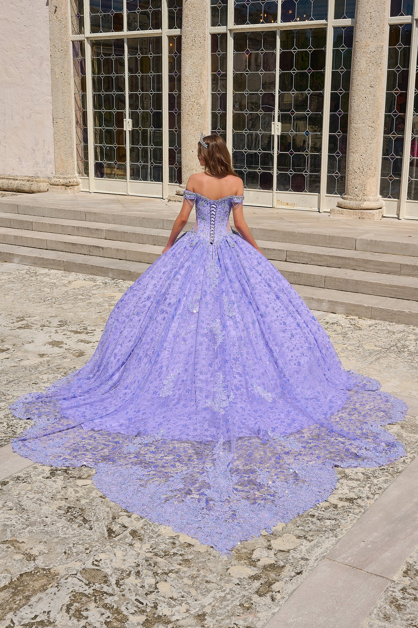 Be the belle of the ball in the Amarra 54220 Quinceanera Ball Gown. This stunning formal dress features a sheer crystal lace train and fringe, for a unique and eye-catching look. The off the shoulder design adds a touch of elegance and the perfect amount of skin. Stand out in style. Unleash your inner princess with our enchanting lace ball gown! Crafted with a dreamy lace fabric adorned with detailed floral pattern