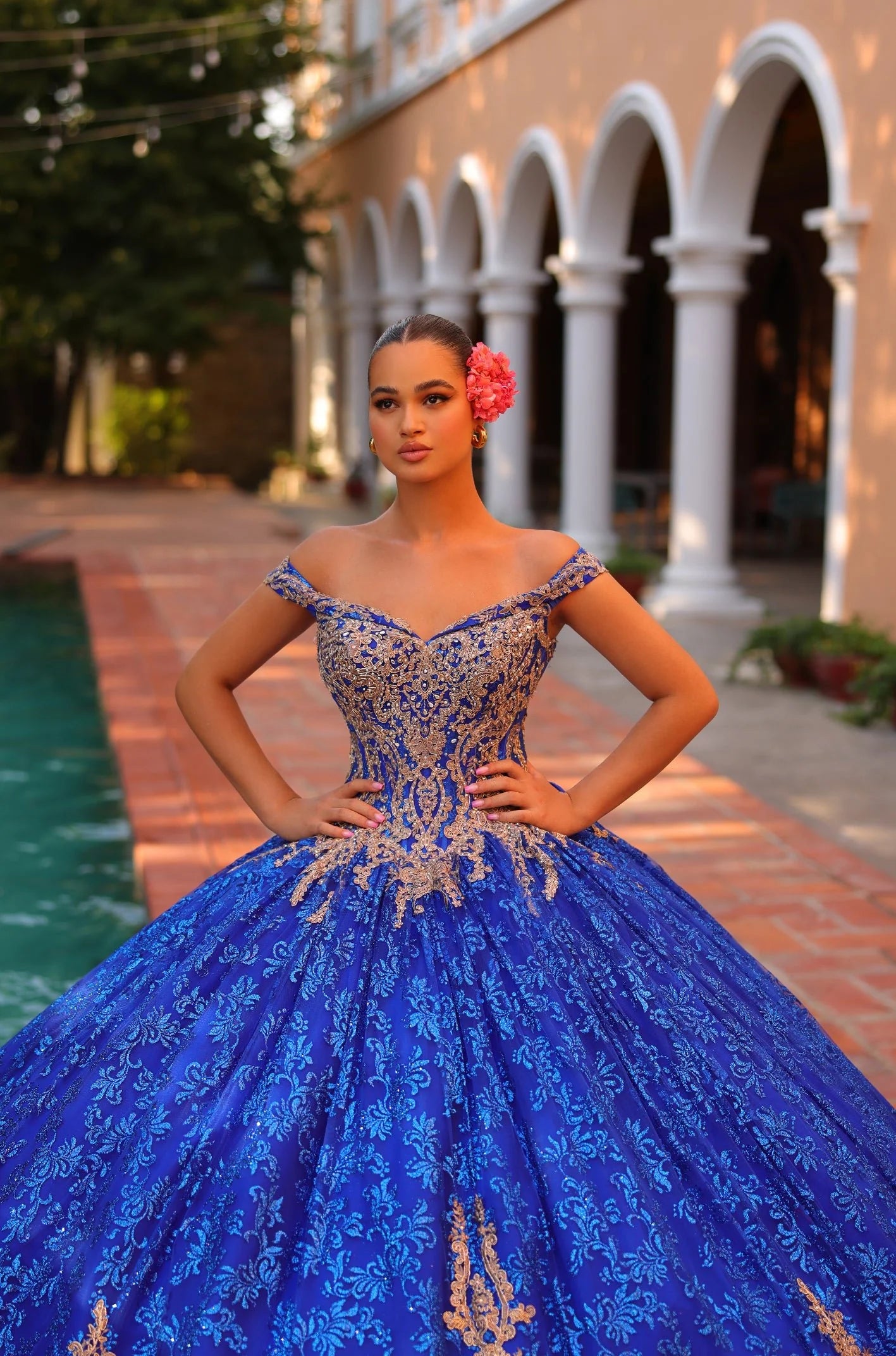 This Amarra 54324 Quinceanera Dress boasts a glittering hooded cape and off-the-shoulder corset, perfect for making a grand entrance at any party or ball. The exquisite train and bow detail add an extra touch of elegance to this stunning gown. Elevate your style with this eye-catching dress.