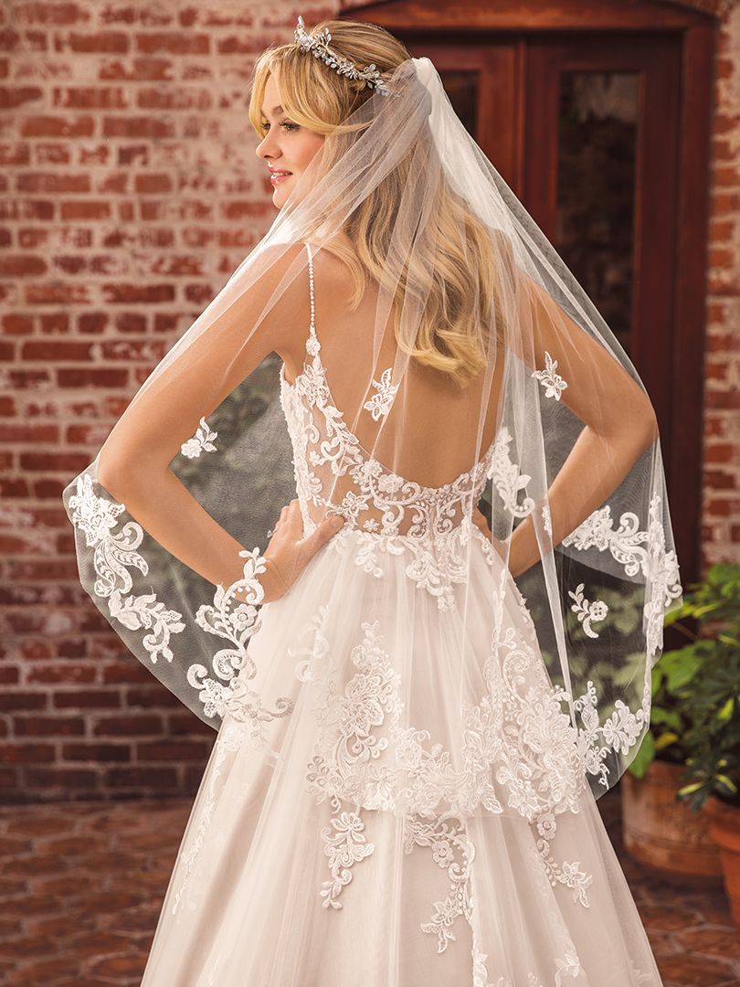 Casablanca Beloved STYLE BL286 DELILAH Other-worldly grace surrounds Delilah, swimming in sateen satin and tulle. Lace appliques cover the bodice and cascade down the flowing skirt of this bohemian wedding gown from Beloved by Casablanca Bridal. Spaghetti straps and a plunging neckline add a seductive touch, transitioning into an alluring illusion lace back. Subtle silver beading catches the light, while a matching veil finishes off this modern boho gown with a glimmer!