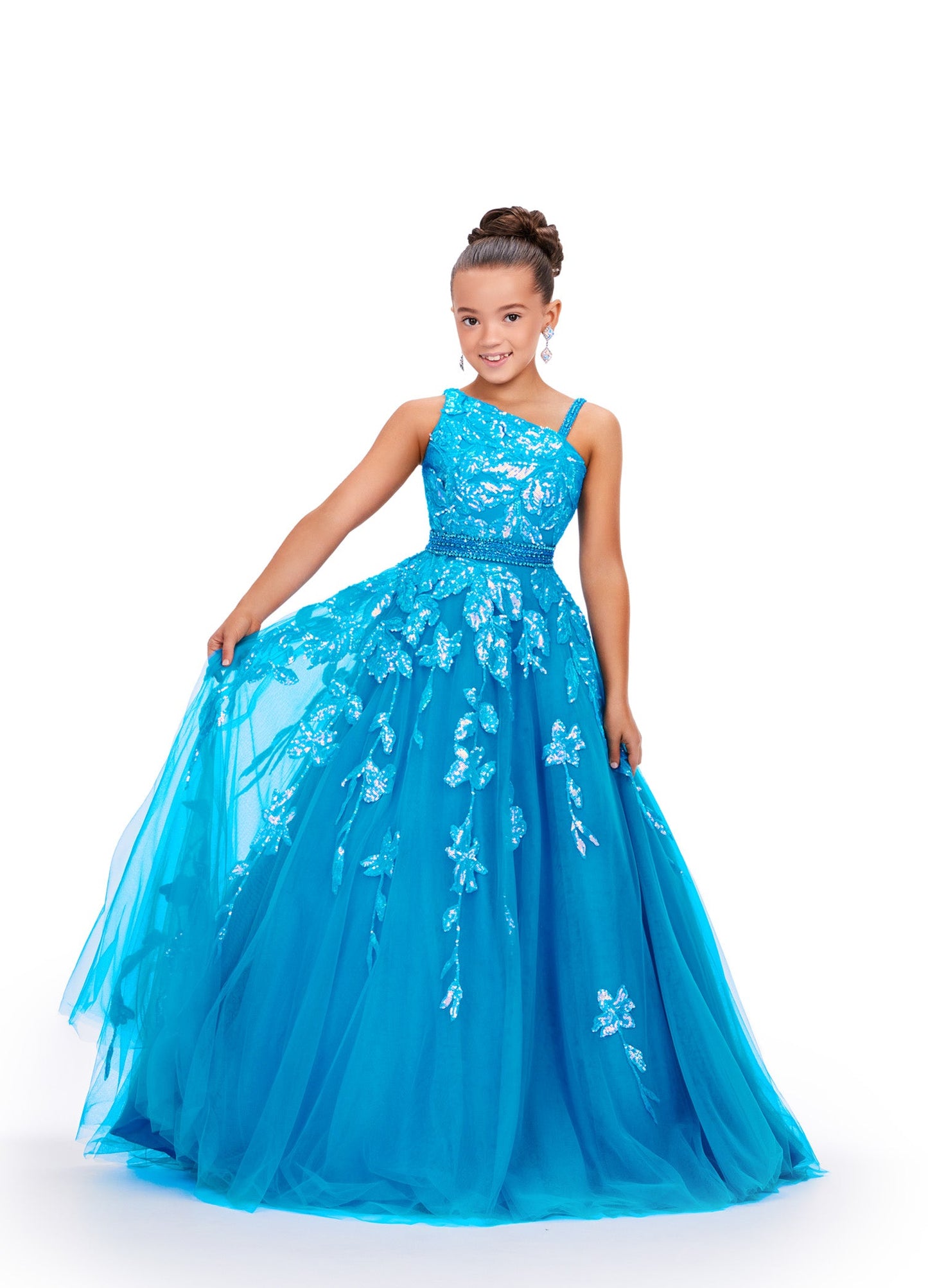 Get ready to dazzle in this stunning Ashley Lauren Kids 8240 Girls Ballgown! With its long tulle skirt and intricate sequin and lace detailing, this one-shoulder dress will make your little one feel like a pageant princess. Expertly crafted, this dress exudes elegance and sophistication. This one shoulder kids tulle ball gown features a sequin applique bodice giving way to a beaded waistline. The sequin applique trickle down onto the full a-line skirt.