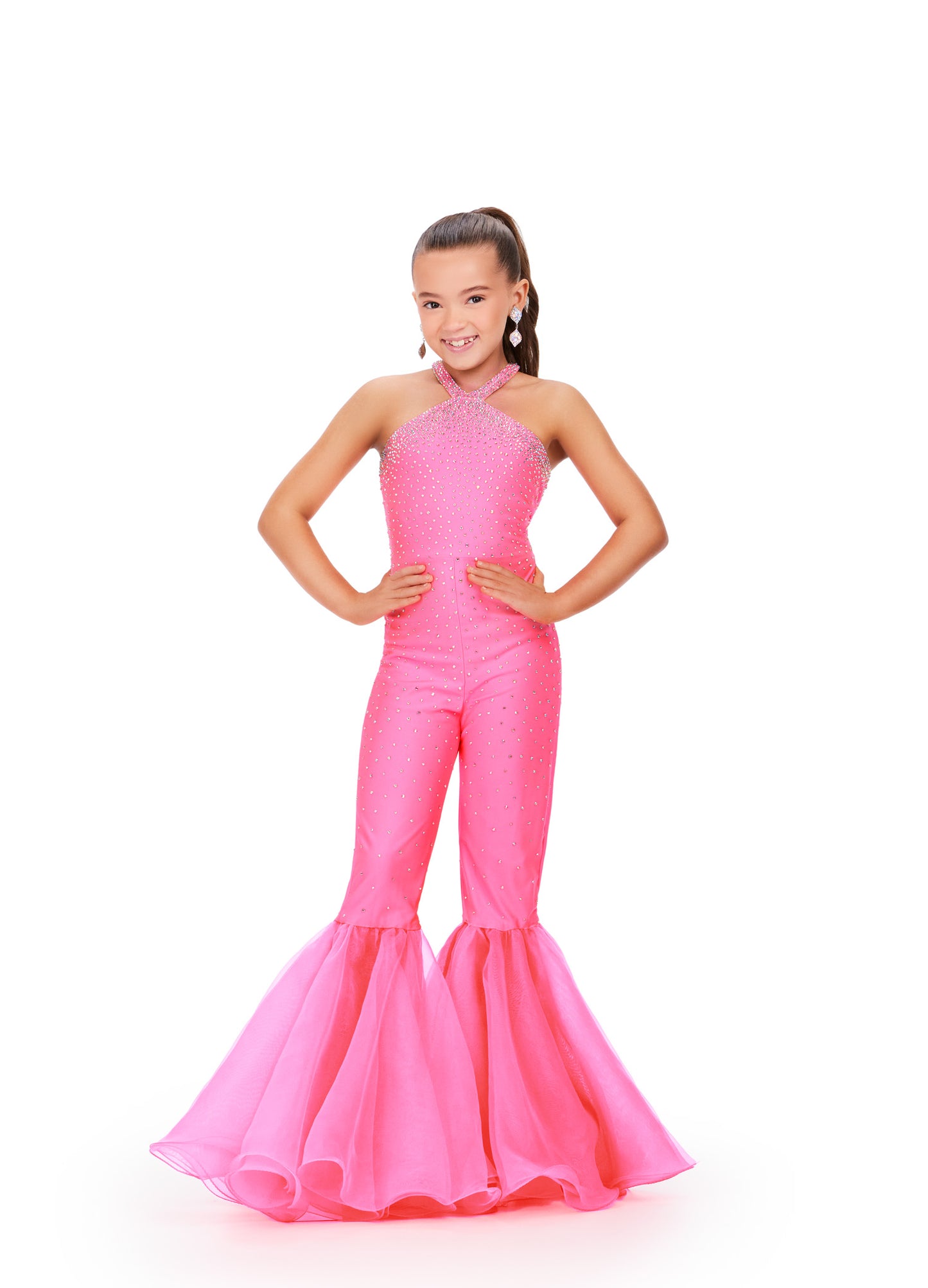 The Ashley Lauren Kids 8265 Girls High Neck Bell Bottom Jumpsuit is a stunning piece designed for pageants. Its high neck and crystal embellishments create an elegant silhouette, while the bell bottom adds a touch of fun. Perfect for standing out on stage, this jumpsuit is a must-have for any young pageant contestant. This super sassy kids jersey jumpsuit features heat set stones throughout and is accented by flared organza bell bottom pant legs.