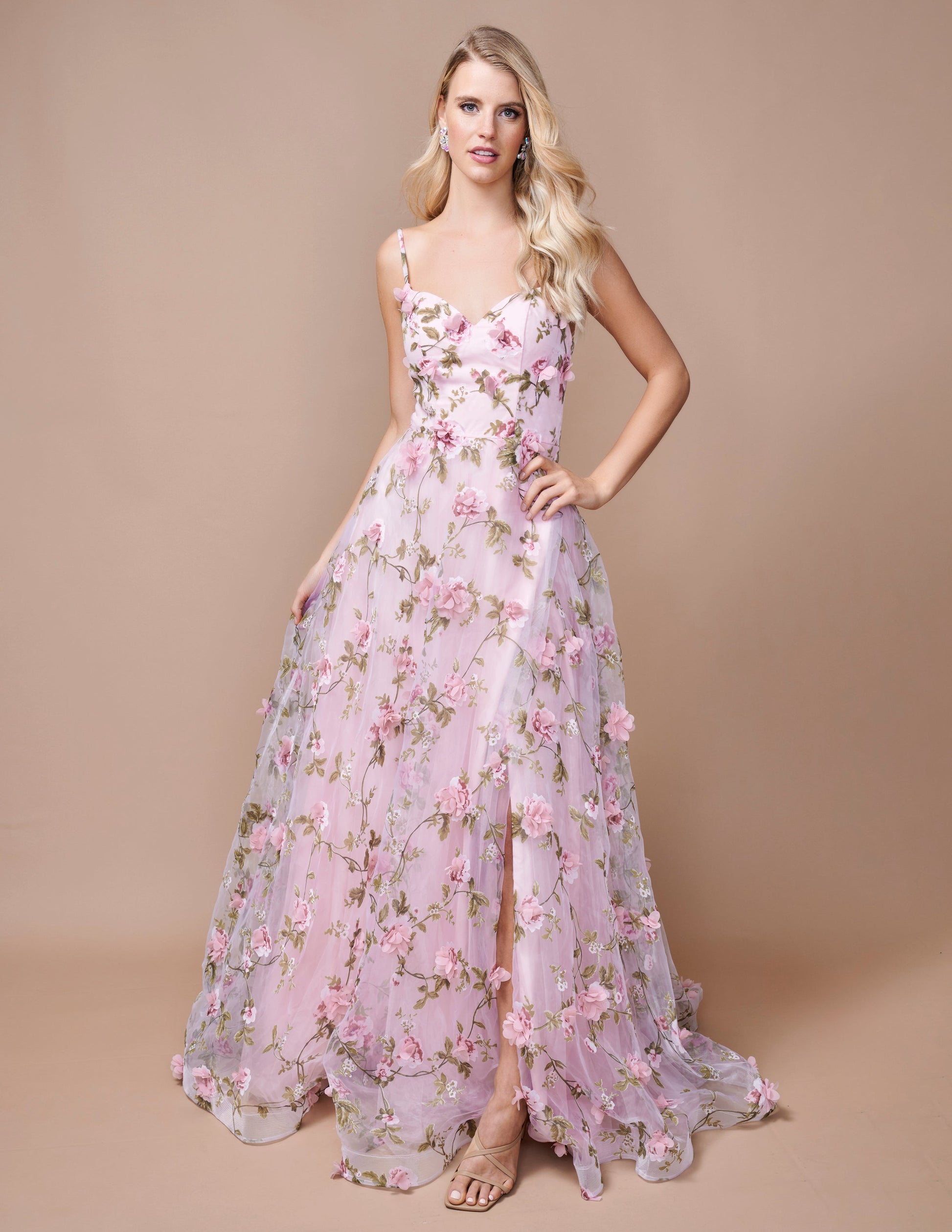 Expertly designed for a sophisticated look, the Nina Canacci 9150 Maxi Dress is the perfect choice for prom or any formal event. This stunning A-line gown features a floral print, 3D detailing, and a V-neckline that will flatter any figure. With a dramatic slit, you'll make a statement as you dance the night away.