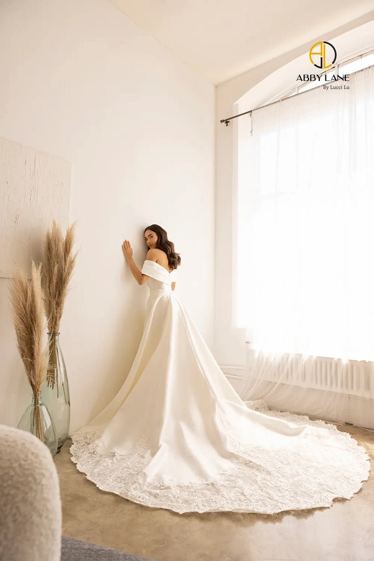 Crafted with Satin and lace, the Abby Lane Bridal 97179 Ivory Gown is a stunningly beautiful A-Line dress with wide, off the shoulder straps. Its train is delicately trimmed with lace for a sophisticated look. Perfect for the special day.  Color:  Ivory