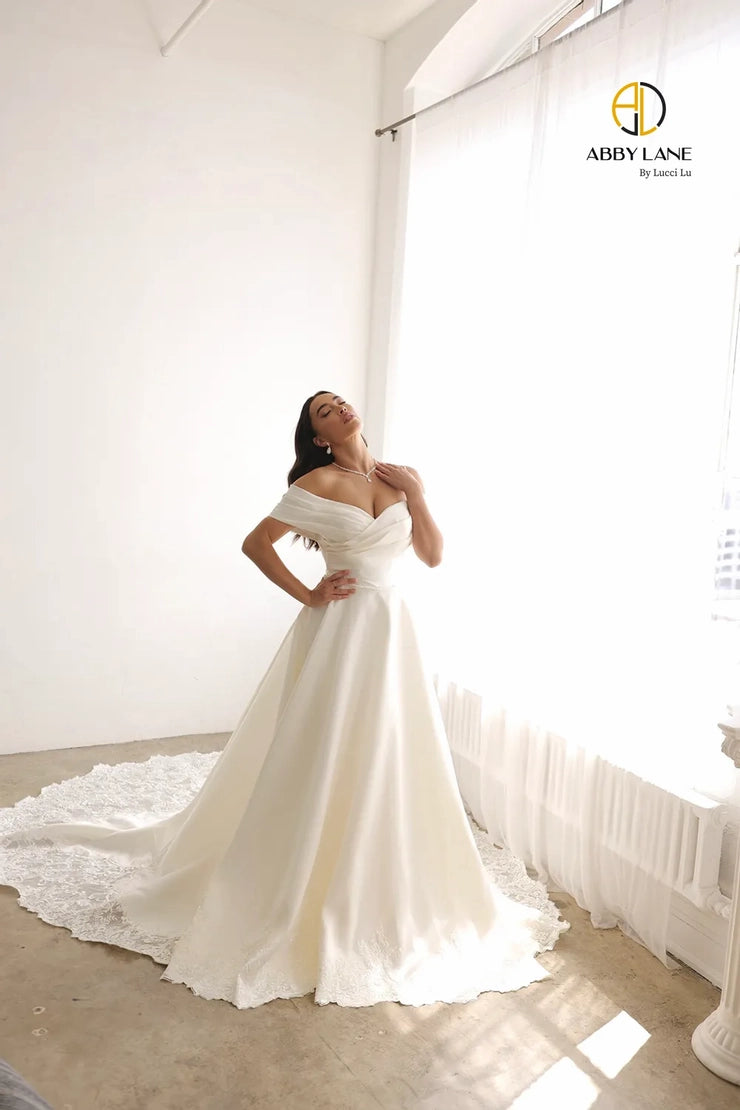 Crafted with Satin and lace, the Abby Lane Bridal 97179 Ivory Gown is a stunningly beautiful A-Line dress with wide, off the shoulder straps. Its train is delicately trimmed with lace for a sophisticated look. Perfect for the special day.  Color:  Ivory