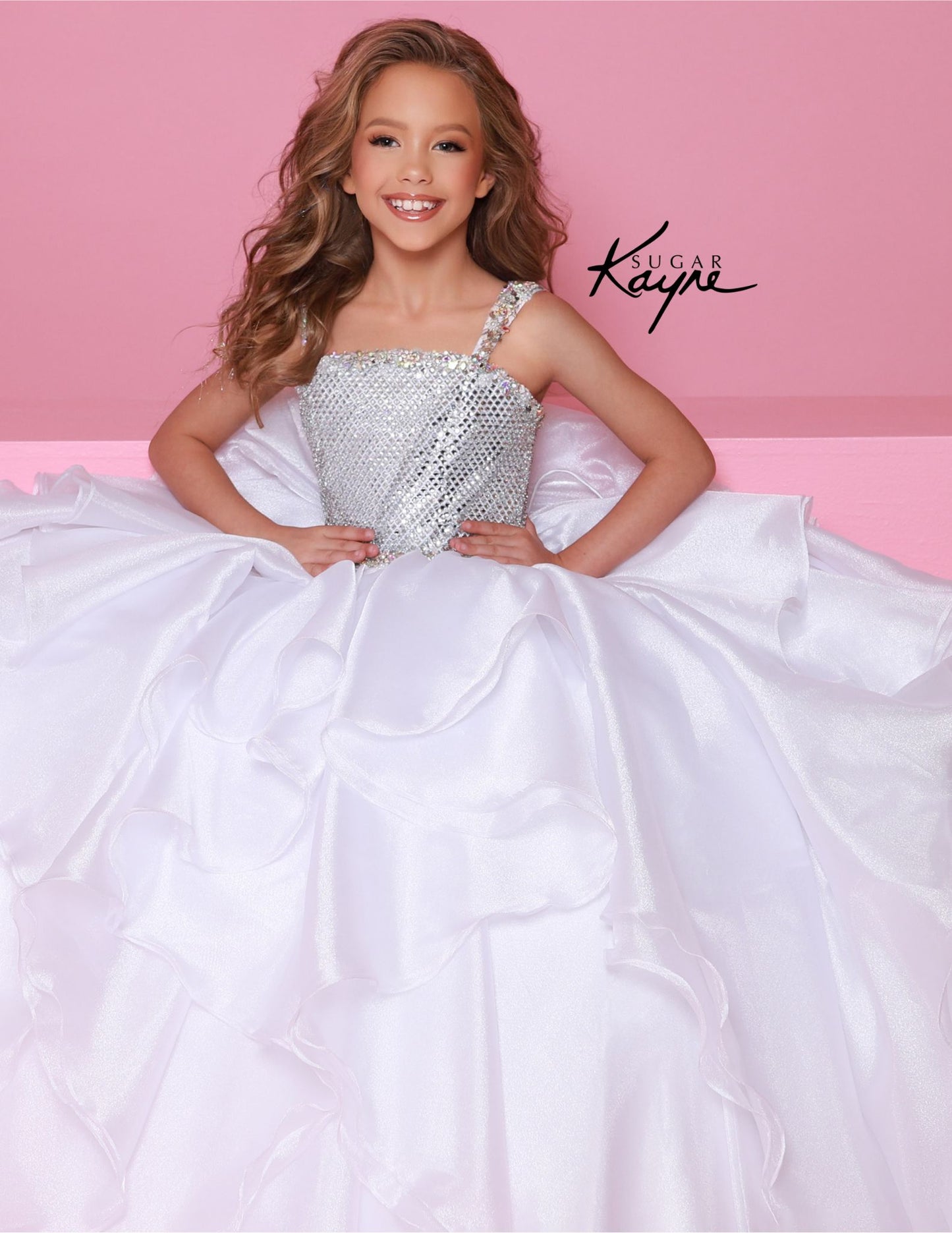 Step onto the pageant stage with confidence in the Sugar Kayne C383 Girls Pageant Dress. This stunning ballgown features a crystal bodice that will shimmer and shine under the lights, while the ruffle detail adds a touch of playful elegance. The layered skirt adds volume and movement, making you the star of the show. Make a dramatic statement at your next pageant with this stunning diamond mesh dress. The ruffled shimmer organza skirt completes the look, offering a perfect blend of elegance and flair.

Size