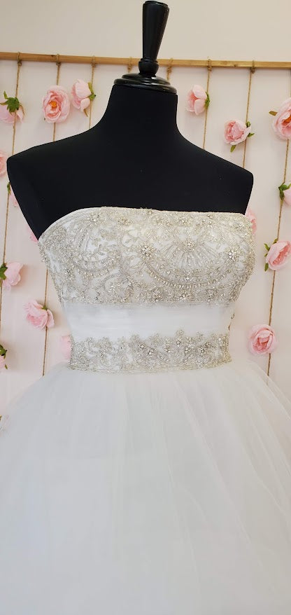 Casablanca Bridal 2052 Soft Tulle pick-ups over Silky Satin accented with heavily beaded bodice and a ruched Tulle waistband this wedding dress is over the top romantic.   Color:  Ivory/Ivory/Silver  Fabric: Tulle over Silky Satin with Beaded and Embroidered bodice.  This is a size 6 in Ivory & Silver