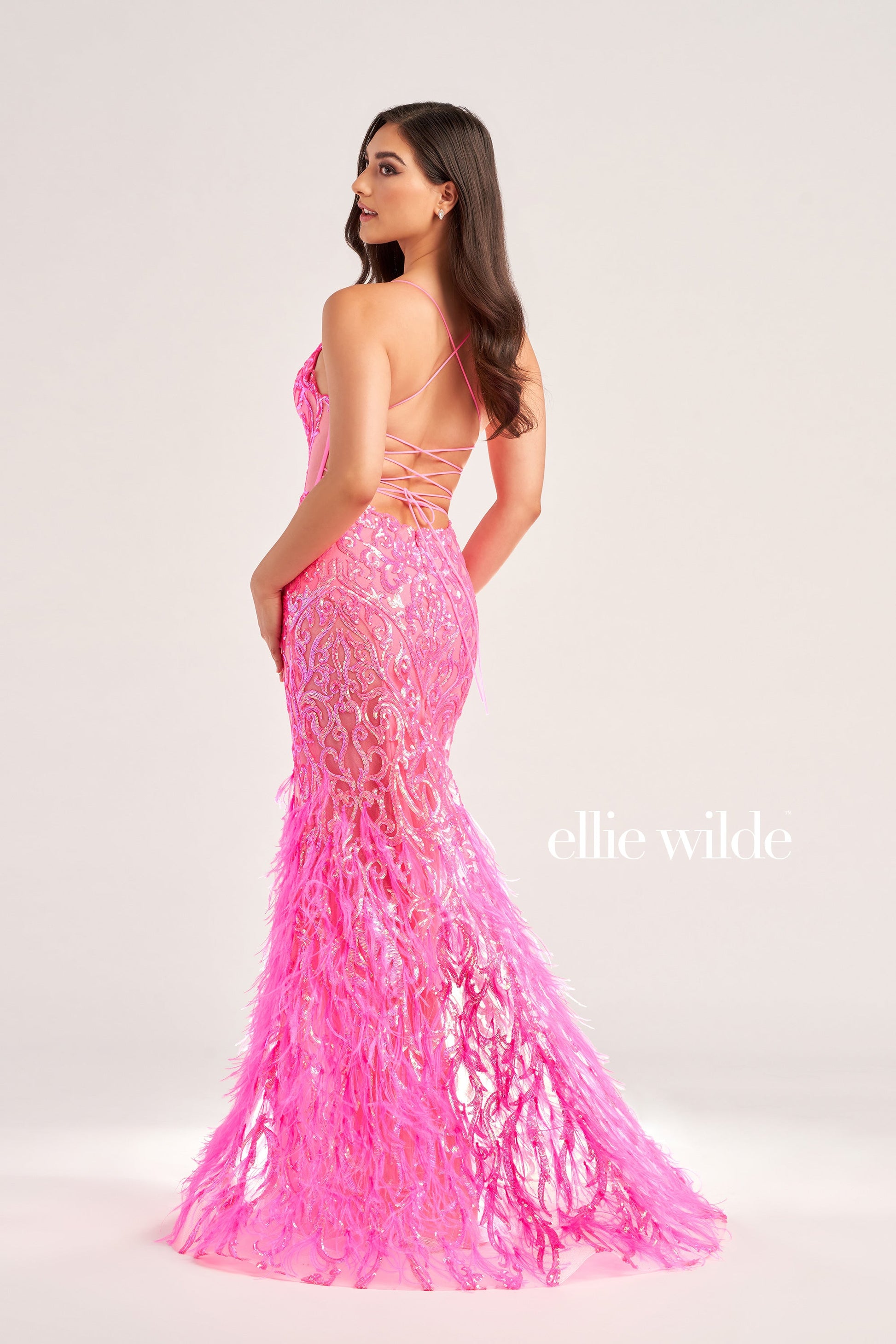 The Ellie Wilde EW35006 Sheer Sequin Prom Dress Gown features a low lace-up back with a side waist mesh inset corset and a glamorous, full-length feather skirt. Look stunning on your special night with this luxurious backless gown.  COLOR: ORANGE, CHAMPAGNE, EMERALD, HOT PINK, IRIS SIZE: 00 - 16