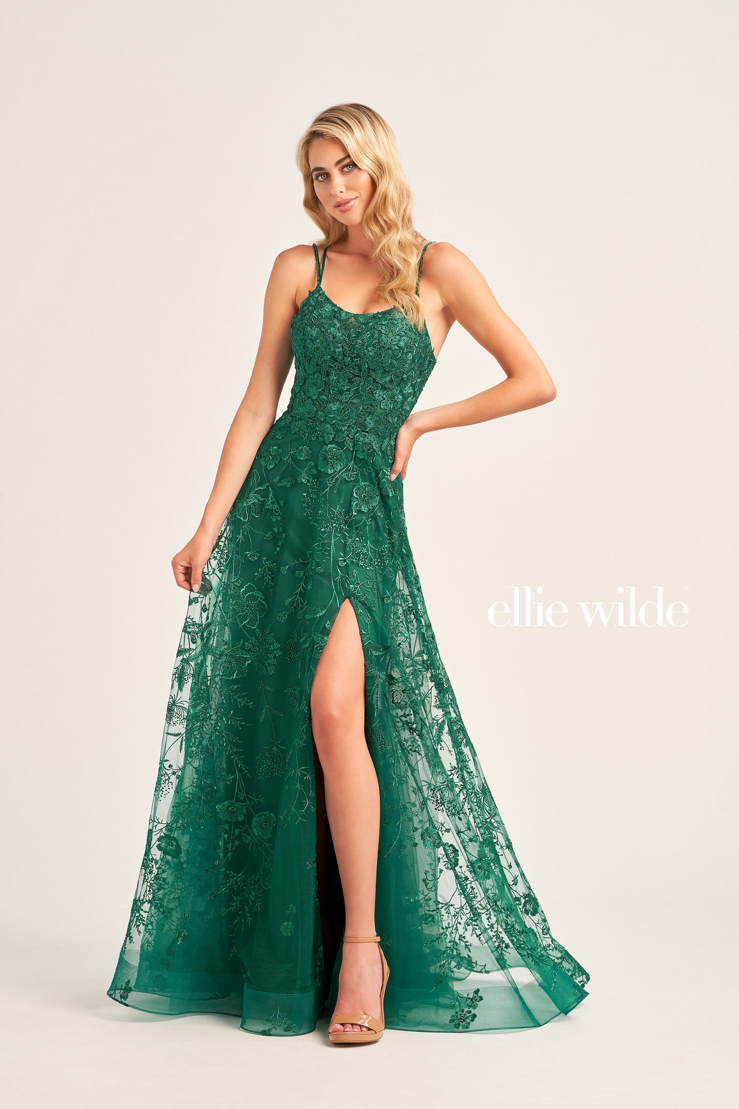 This Ellie Wilde EW35012 Formal Gown is the perfect blend of style and comfort. Crafted with beautiful embroidered tulle, lace, and stone accents, this dress features a long length, scoop neckline, and A-line silhouette. Practical and eye-catching, this gown has pockets, a high slit, and a lace-up back, all draped on a flattering natural waistline. A perfect pick to shine in style at your next event.  COLOR: MAGENTA, EMERALD, STRAWBERRY, BLUEBELL SIZE: 00 - 24