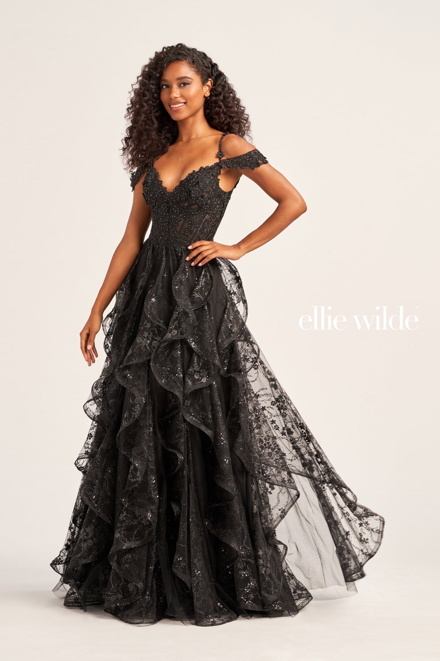 This Ellie Wilde EW35218 prom dress is a show-stopper. It features a sheer corset bodice with stone accents, lace appliques, and sequins. The detachable draped off-shoulder straps perfectly match the plunging sweetheart neckline. A-line silhouette in a long cracked ice tulle skirt adds to its timeless elegance. Make your grand entrance and shine the night away.  COLOR: BLACK, PINK, EMERALD, NAVY, WHITE