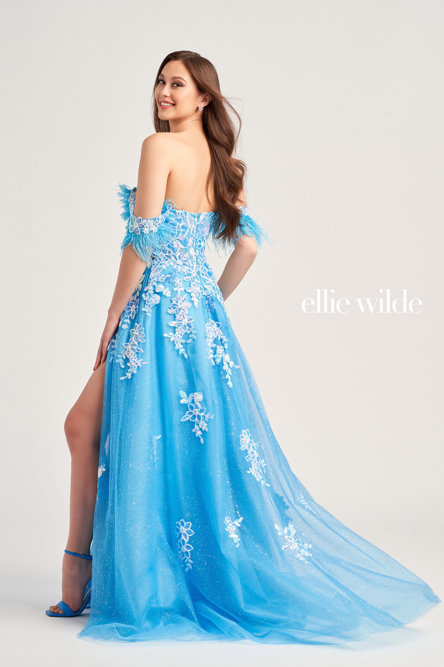 Look stunning at special occasions in this Ellie Wilde EW35220 ball gown. Crafted with a glitter tulle bodice, sequin appliqués, and a detachable draped off-shoulder feather strap design, this A-line silhouette features a plunging sweetheart neckline, pockets, a high slit, and separate spaghetti straps. The natural waistline sits above the long tulle skirt for an unforgettable red carpet-worthy look.  COLOR: EMERALD, HOT PINK, CERULEAN BLUE