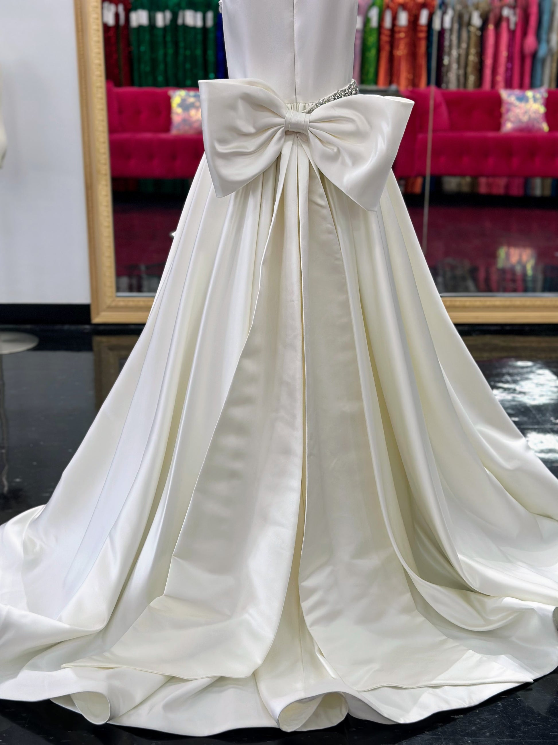 This Ashley Lauren 8079 Size 12 Ivory Long satin A Line girls Pageant Dress features an elegant crew neckline, a crystal encrusted waistline, and an A-line skirt that is complemented by a detachable bow at the back. Perfect for formal occasions, this high-quality gown will make your little girl look beautiful.