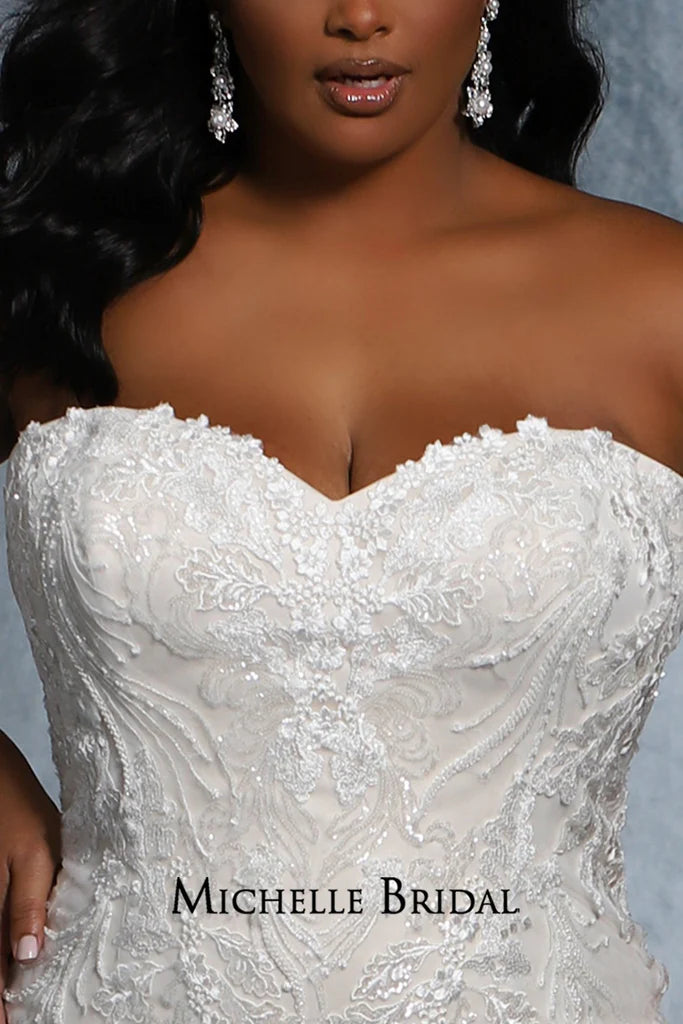 The Michelle Bridal for Sydney's Closet MB2117 is a stunning plus-size bridal gown featuring a strapless sweetheart neckline, lace-up back, and fitted silhouette adorned with floral appliques and pearls. Made with sequins for added sparkle, this striking gown will be sure to make any bride's special daydream come true.