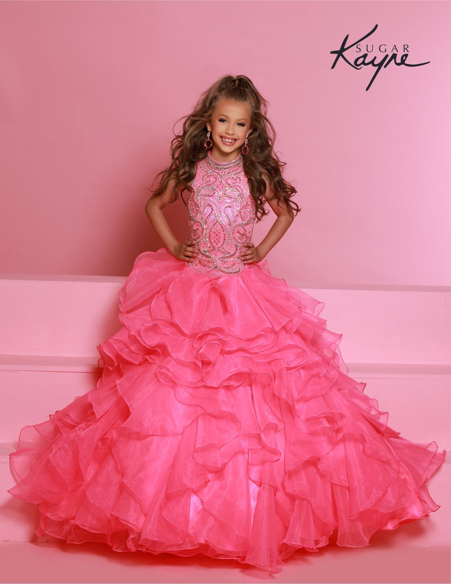 Sugar Kayne C326 Barbie Pink is the perfect pageant dress for young girls and preteens, featuring a ruffled long skirt, high neckline, and crystal bodice with sleeveless design.