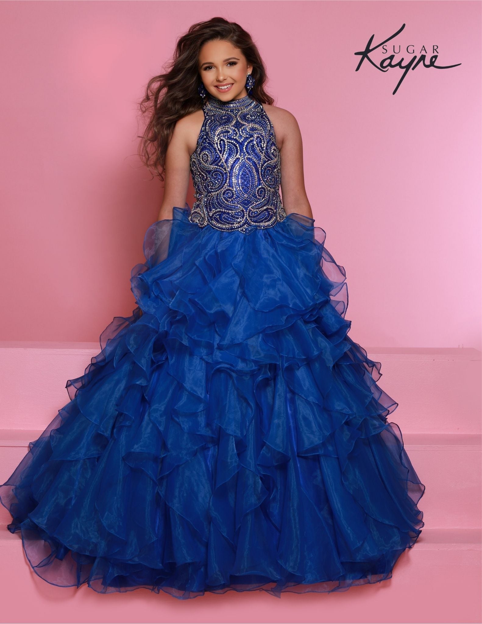 Sugar Kayne C326 royal blue is the perfect pageant dress for young girls and preteens, featuring a ruffled long skirt, high neckline, and crystal bodice with sleeveless design.