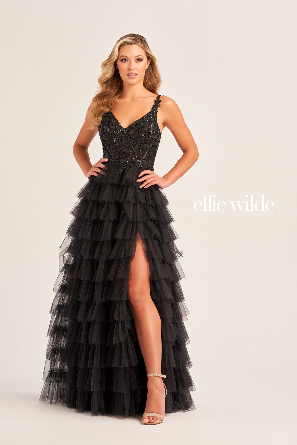 This Ellie Wilde EW35059 prom dress exudes elegance and glamour. The long tulle layers, A-line silhouette, and lace Sequin corset enhance your natural curves, while the maxi slit and sequin details add a touch of sparkle. Perfect for prom or any formal event, this dress is sure to make a statement.  Sizes: 00-20  Colors: ﻿BLACK, MAGENTA, ROYAL BLUE, BARBIE PINK