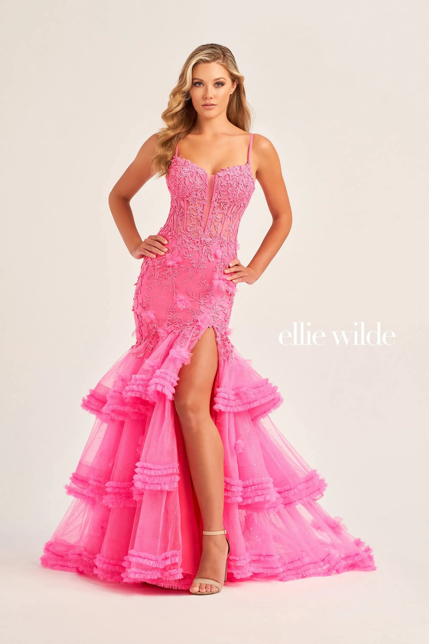 Be the star of the night in this Ellie Wilde EW35050 prom dress. The sheer lace corset with 3D dimensional appliques creates a flattering silhouette while the Tiered Tulle pleated ruffle layered trumpet skirt features a slit and shimmer fabric add a touch of glamour. The pleated mermaid skirt and slit offer both elegance and comfort.  Sizes: 00-16  Colors: OCEAN BLUE, LIGHT BLUE, HOT PINK