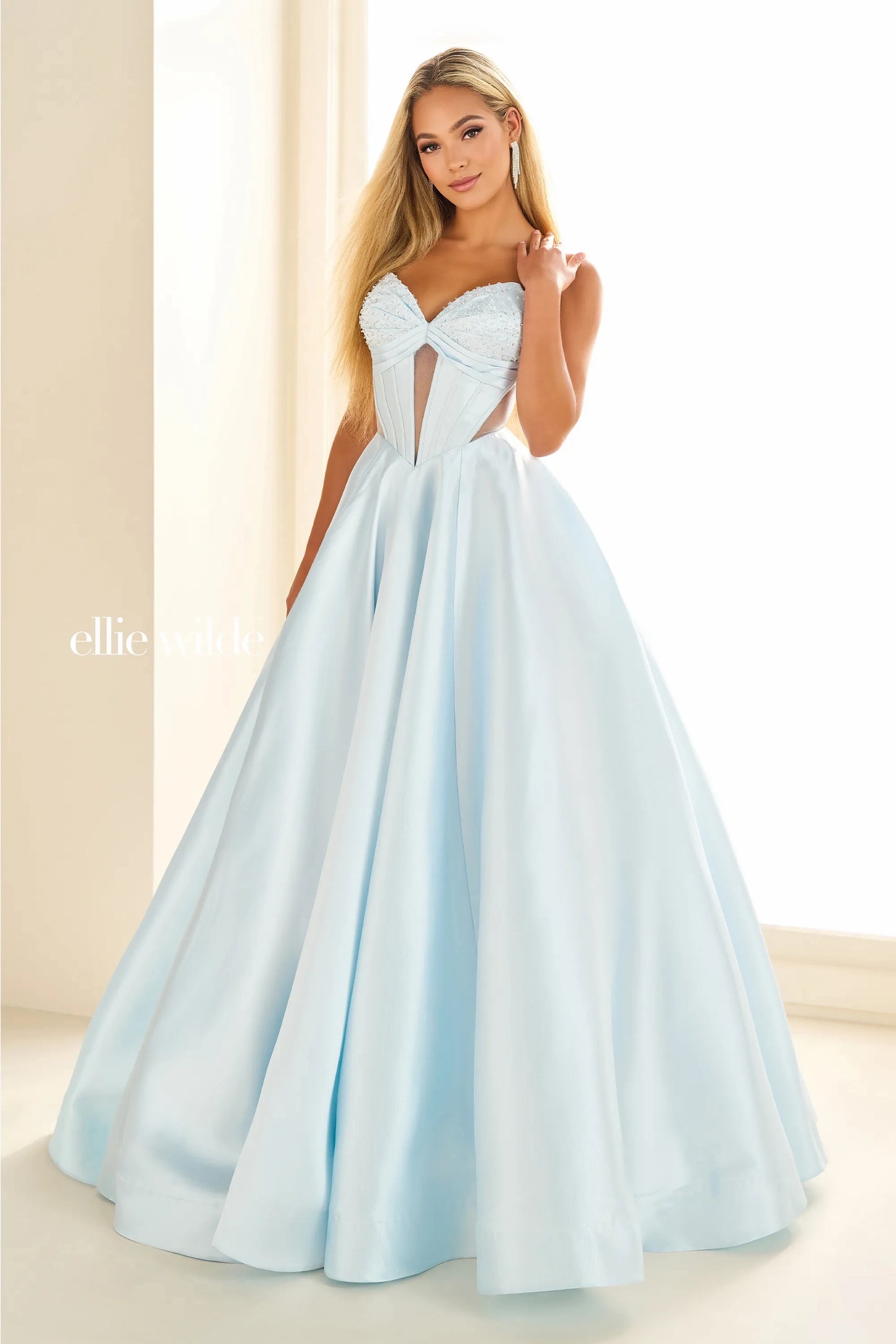 This Ellie Wilde EW36025 prom dress features a stunning A-line silhouette with sheer ballgown detailing and a corset back for a perfect fit. The dress also includes convenient pockets and cut-out design, making it both fashionable and functional for any pageant or formal event.