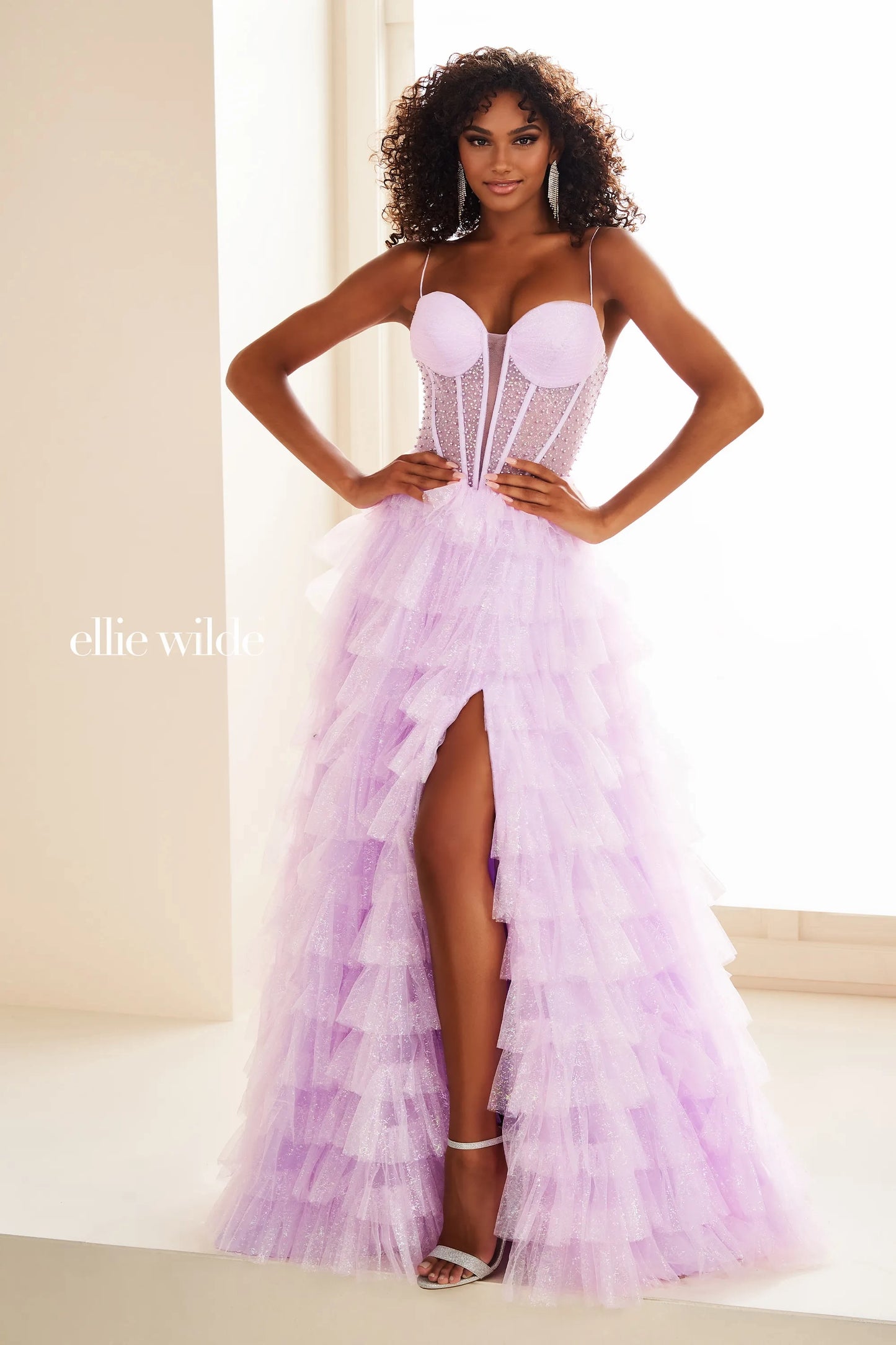 Expertly designed by Ellie Wilde, this prom dress EW36029 features a sheer corset and layered slit for a stunningly elegant look. The shimmering pearl details and pageant-worthy style make it a perfect choice for any formal event. Elevate your style with this statement gown. Layered maxi slit shimmer skirt.