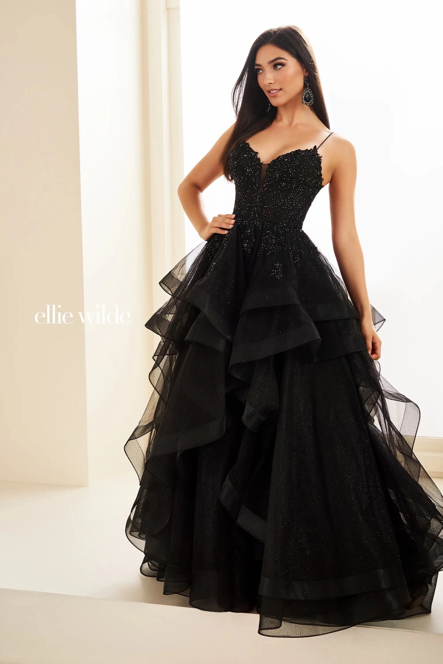 This Ellie Wilde EW36203 prom dress dazzles with a sheer lace corset bodice, ruffle A-line skirt, and shimmering fabric. Create an elegant silhouette with the figure-flattering corset and add a touch of romance with the feminine ruffle detailing. Perfect for a formal evening event, this dress is sure to turn heads.