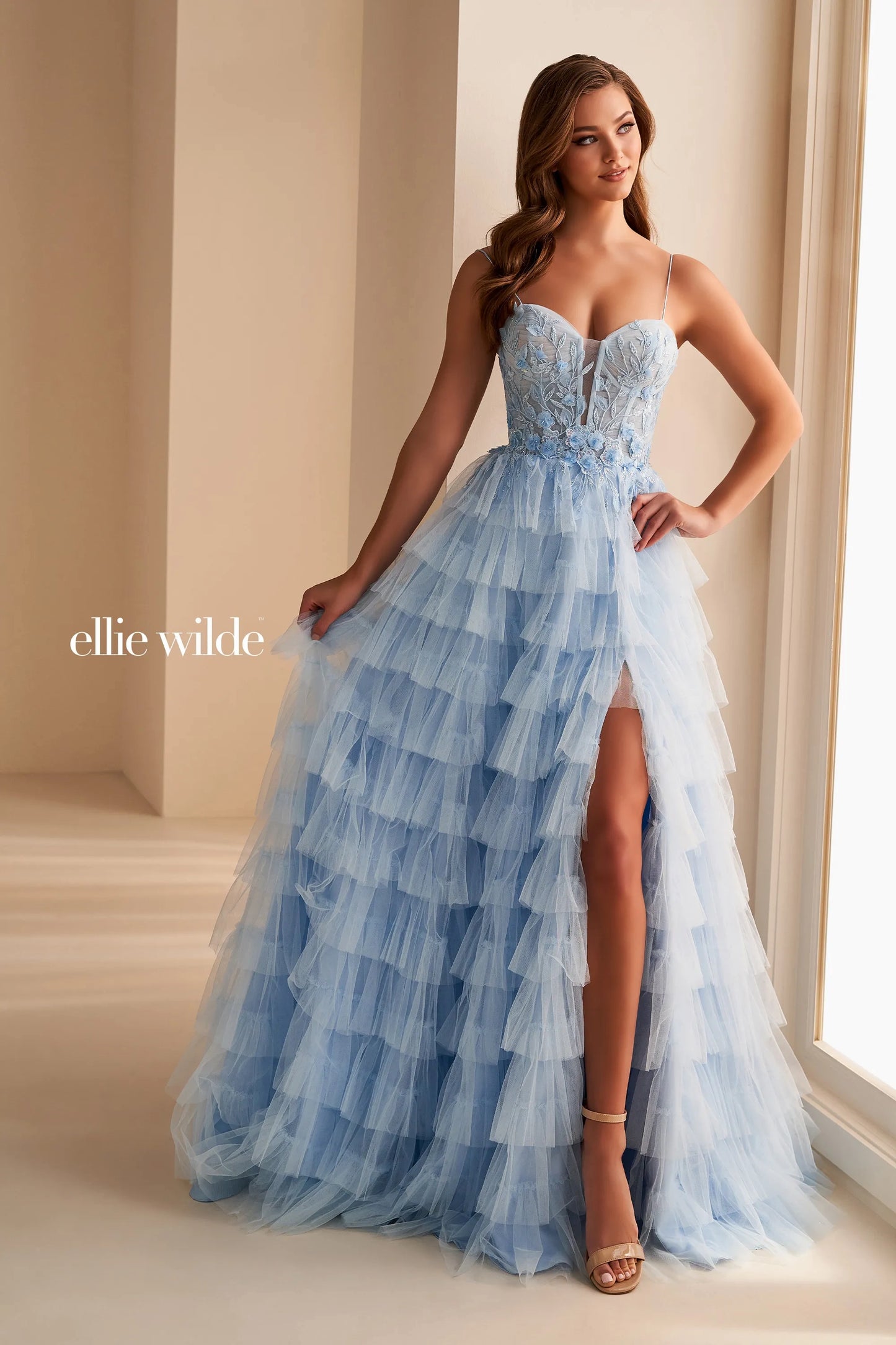 Elevate your prom night in this stunning Ellie Wilde EW36223 prom dress. The long tulle layers create a flowing silhouette, while the sheer lace corset adds a touch of delicate beauty. Complete with a dramatic maxi slit, this formal gown is perfect for making a lasting impression.