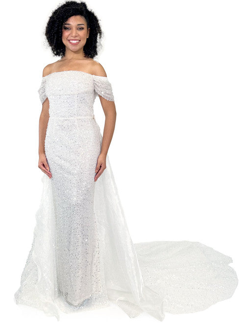 This Marc Defang 8228 dress is an elegant, fitted off-the-shoulder design, featuring a detachable overskirt and ornate pearl, sequin, and beaded detailing. It's perfect for a unique prom, pageant, or wedding look. Corset back  Sizes: 00-16  Colors: Hot Pink, White  *Allow 30 days production