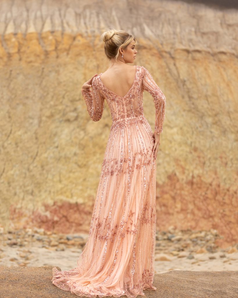 Primavera Couture 3685 This long beaded evening gown has a bateau neckline and long embellished sleeves.  The A line design is beaded to the floor and has a boho tone. Available colors:  Champagne, Black Multi  Available sizes:  0-24