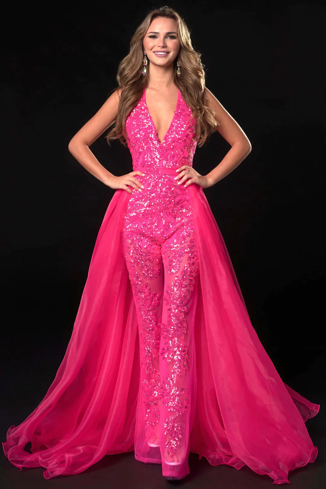 Ava Presley 37381 is crafted with a long, sheer sequin halter jumpsuit, detachable overskirt, V-neck backless design, and a hint of fun fashion. The result is a luxurious, glamorous look perfect for pageants.  Sizes: 0-16  Colors: Royal, Fuchsia, Iridescent Orange