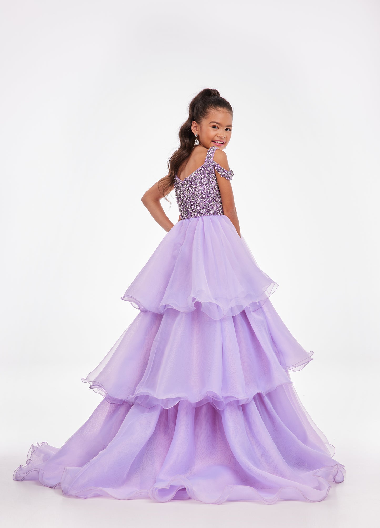 Ashley Lauren Kids 8101 Girls Pageant Dress.  The crystal encrusted bodice on this kids Pageant Gown consists of a slight V-Neckline and off the shoulder straps. The A Line multi-tiered organza ruffle skirt completes the look with a long train.   Available colors:  Hot Pink, Lilac, Turquoise