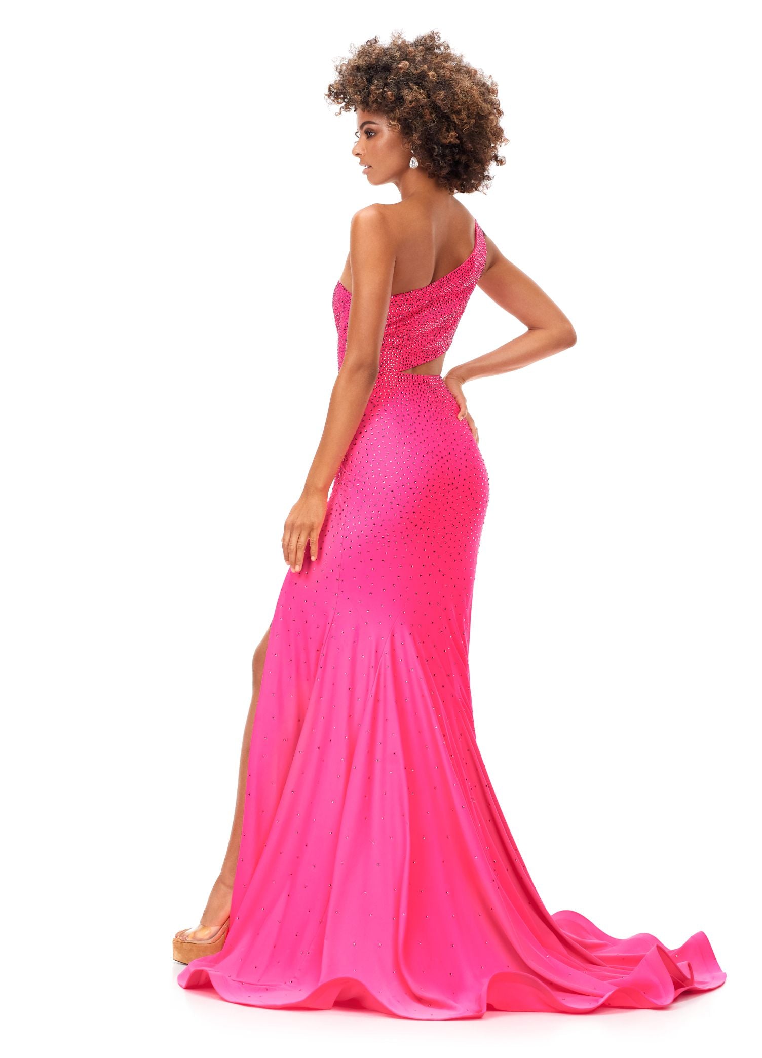 Ashley Lauren 11337 Stand out in this fitted one shoulder jersey gown embellished with heat set stones. The look is complete with an asymmetrical sharkbite cut out and left leg slit. One Shoulder Cut Out Heat Set Stones Jersey COLORS: Hot Pink, Turquoise, Black, Red, Violet