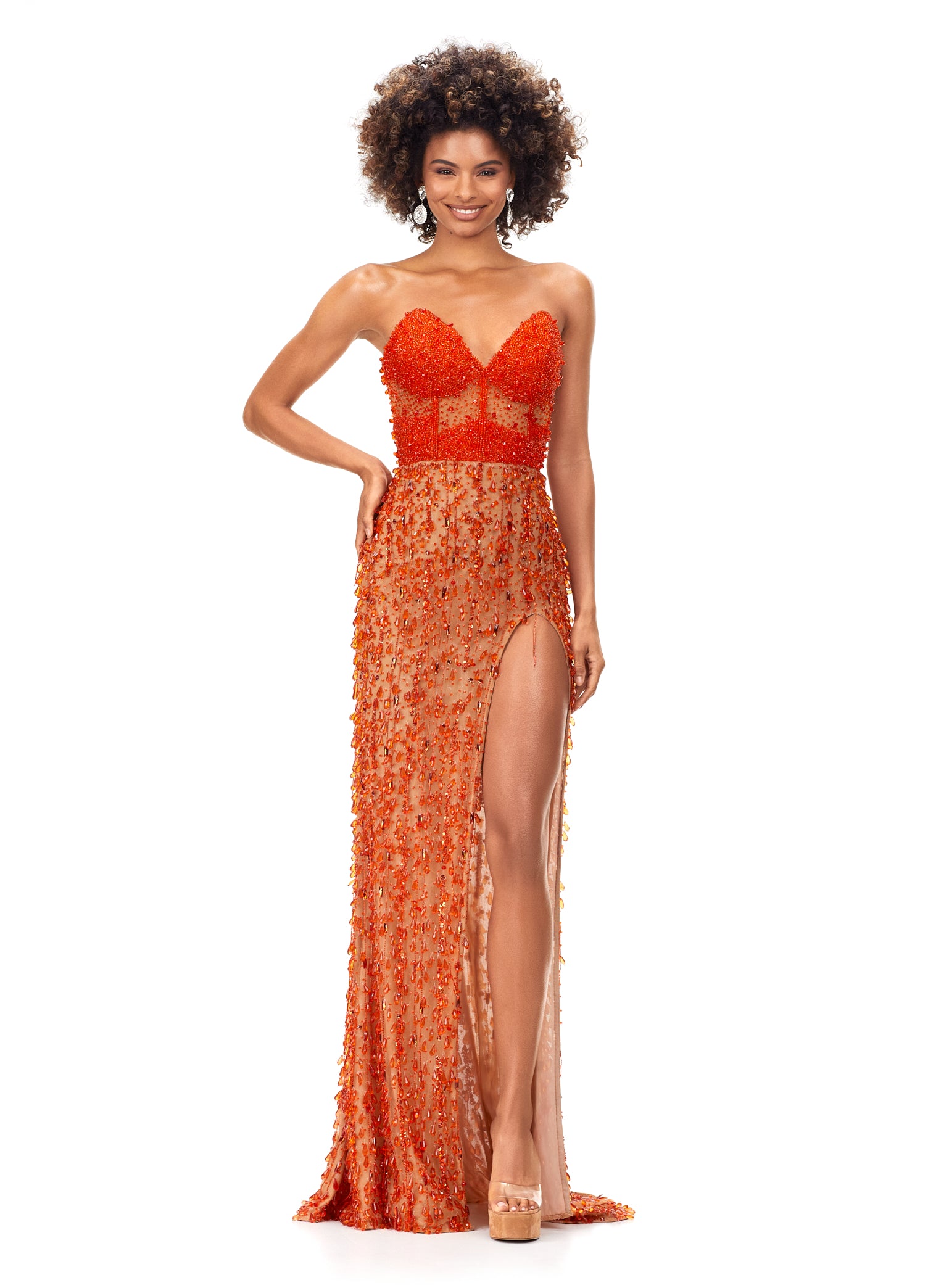 Ashley Lauren 11275 This stunning strapless evening gown features an illusion corset bustier embellished with beading. The fitted skirt is complete with fringe and a left leg slit. Sweetheart Neckline Illusion Corset Bustier Left Leg Slit Fringe COLOR: Orange