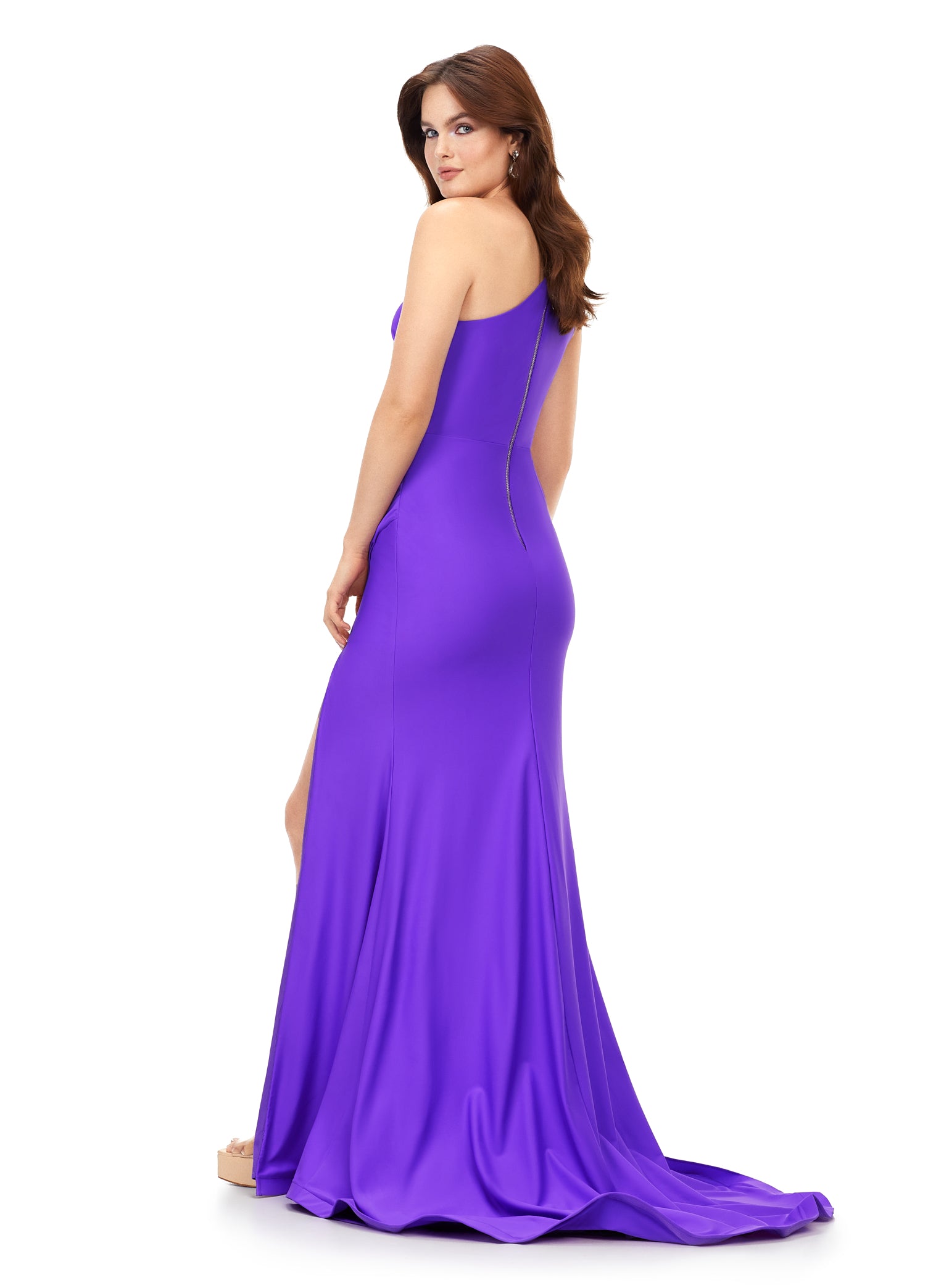 Ashley Lauren 11303 This one shoulder jersey gown features a ruched bodice with asymmetrical cut outs. The ruching continues onto the fitted skirt with slit. The look is complete with an exposed metal zipper back.