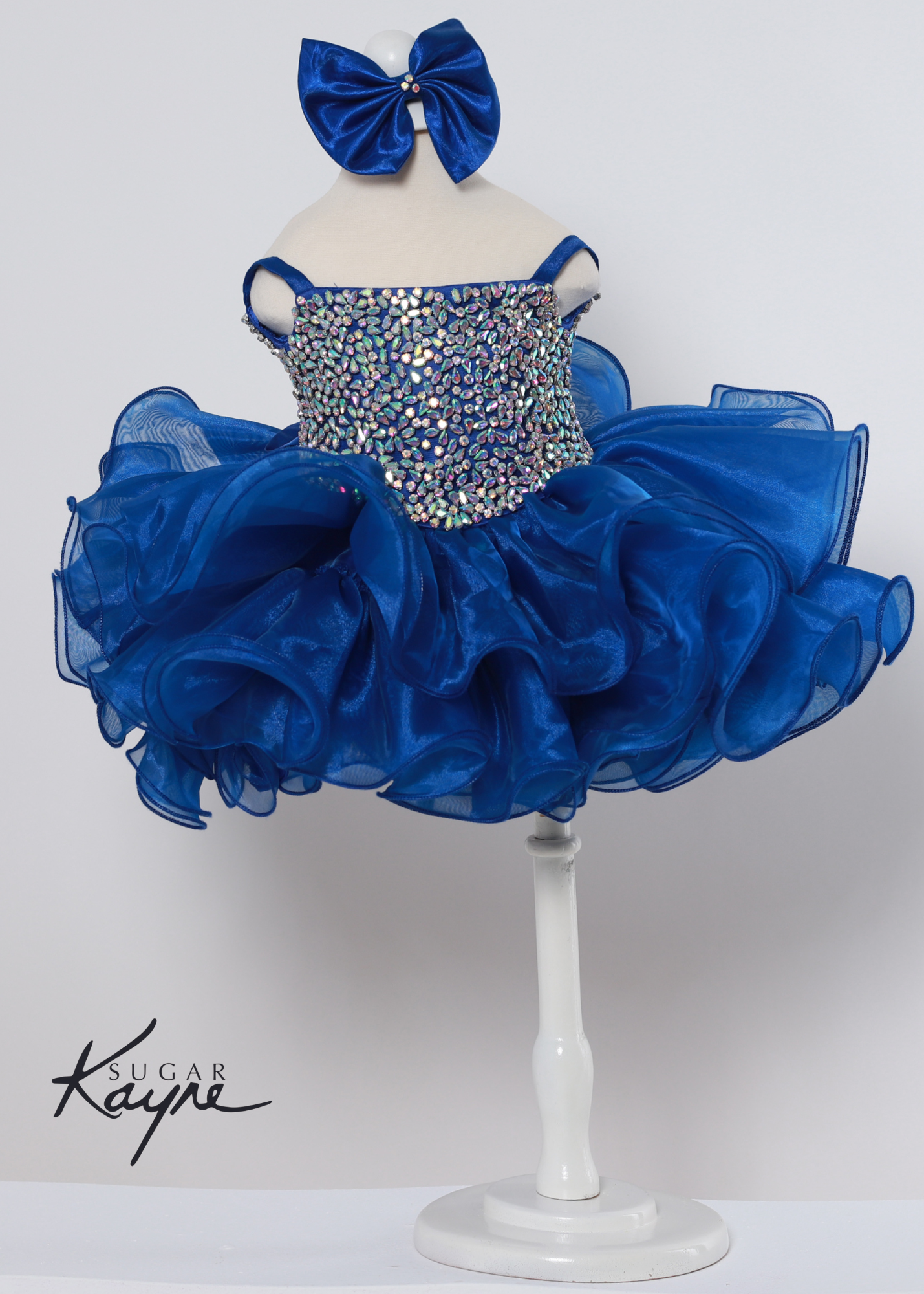 Add a touch of sparkle to your special occasion with the Sugar Kayne C226 Dress. It features intricate rhinestones and a corseted back for adjustable comfort, making it the perfect pageant gown for growing kids. The unique organza ruffles bring a delightful finish for a truly stunning look.  Sizes: 0M, 12M, 18M, 24M, 2T, 3T, 4T, 5T, 6M, 6T  Colors: Barbie Pink, Kiwi, Royal